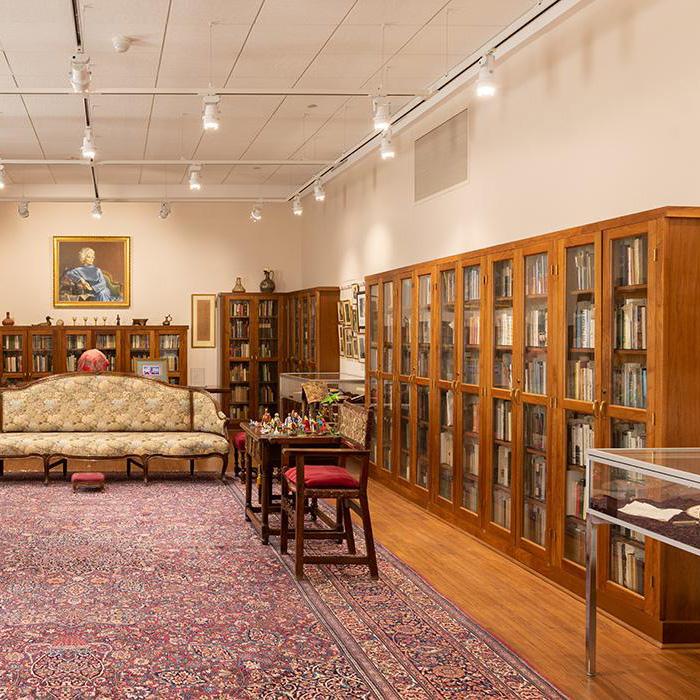 Photograph of one side of the Katherine Anne Porter soon with bookshelves, a couch, an oriental rug, and a portrait of Porter