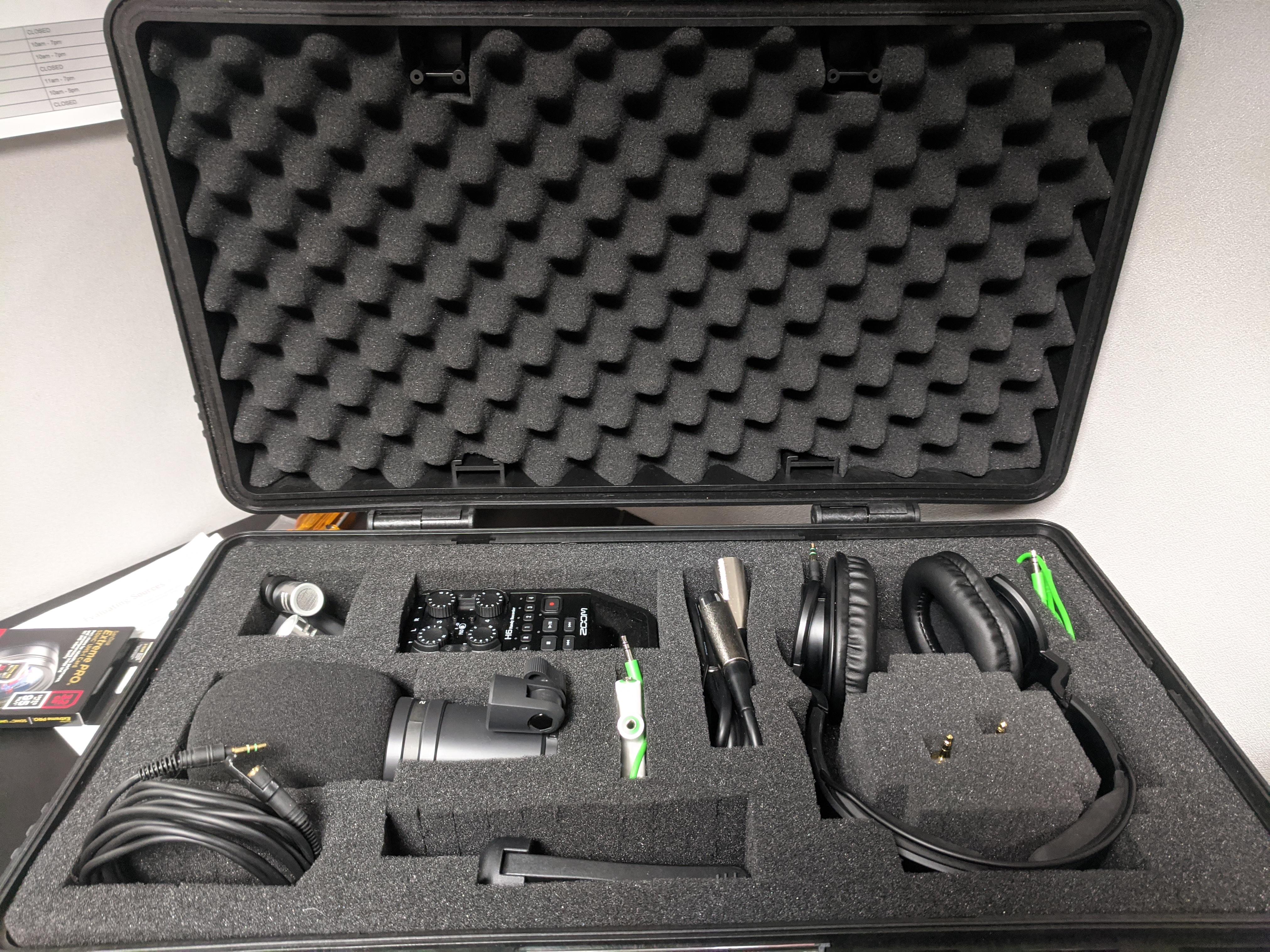 Case with an open lid showing audio recording equipment packed in protective foam