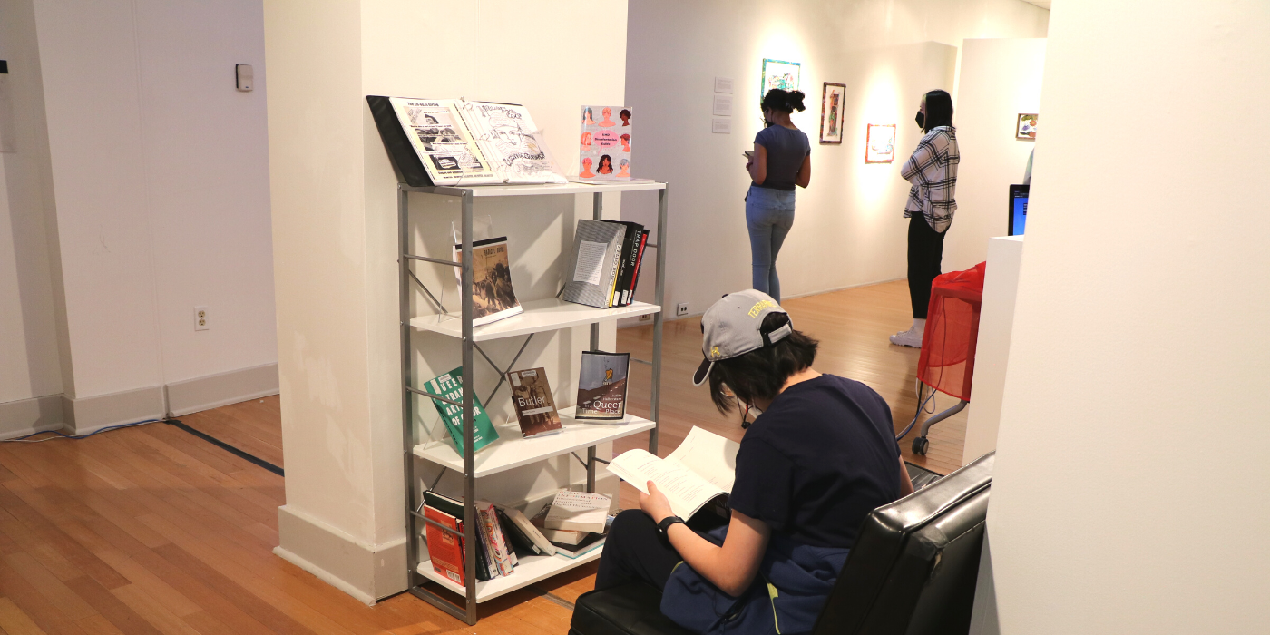 Student reading at the pop-up library in the stamp gallery exhibit.