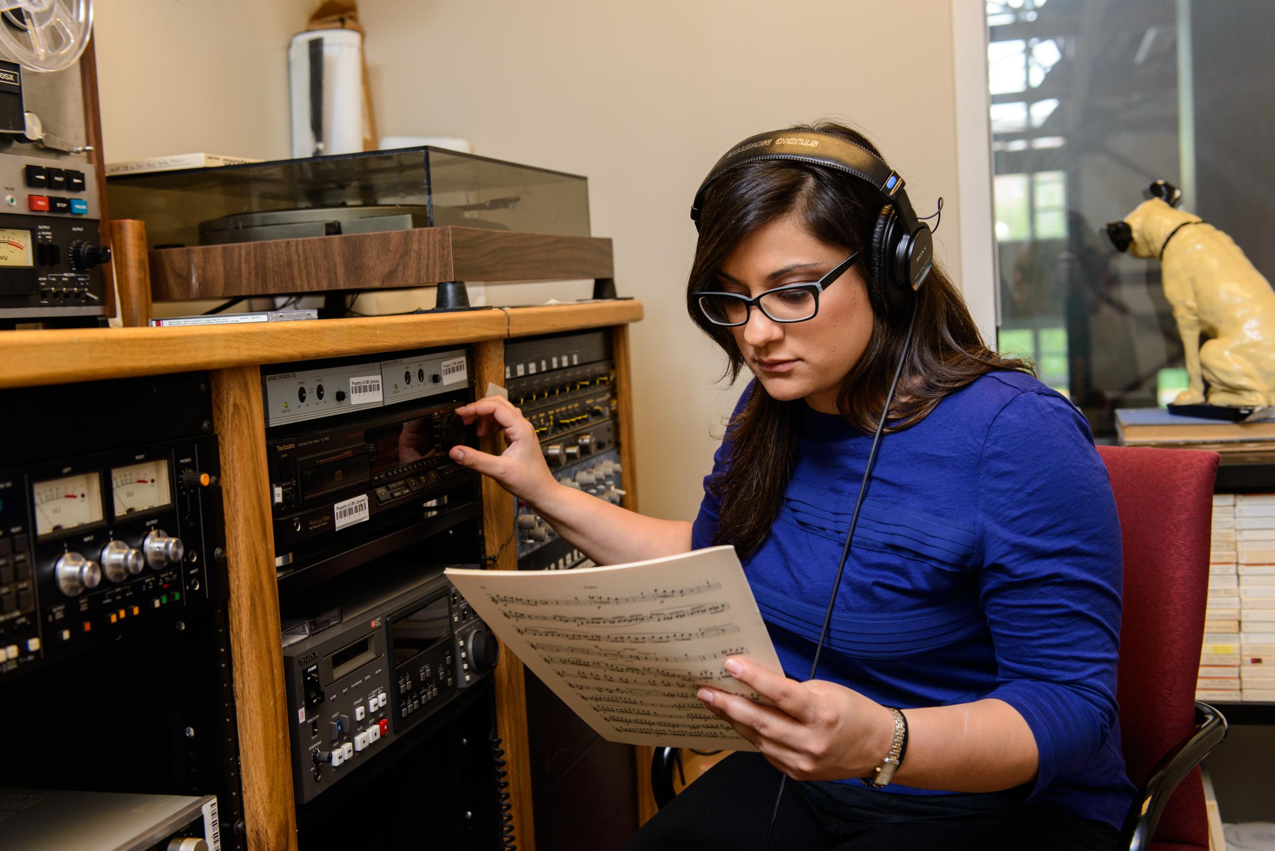 young woman listening to headphones and reading a score