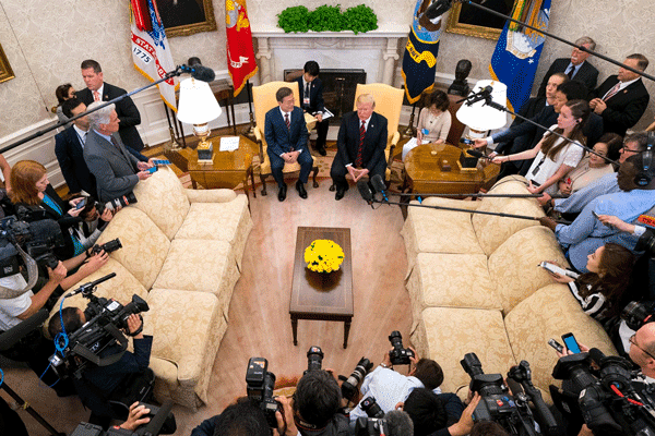 Image of White House Press core surrounding President Trump.