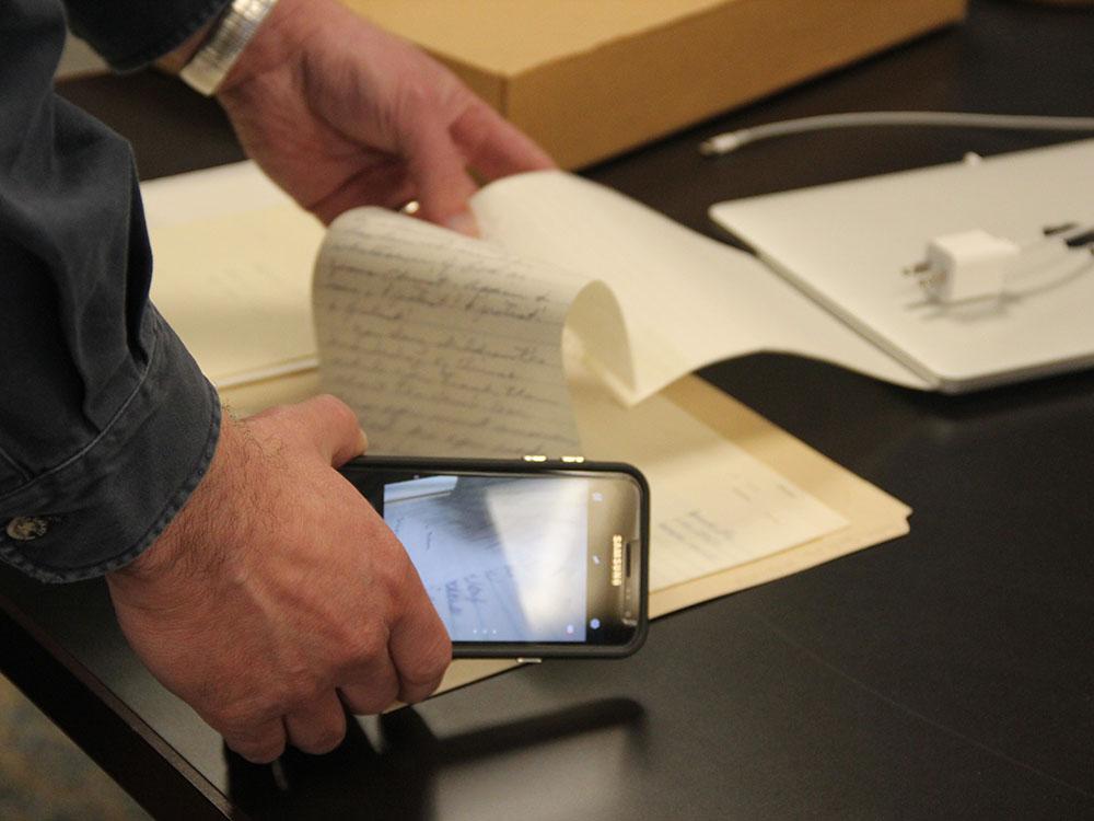 Researcher with camera using archival material in the Maryland Room in Hornbake Library