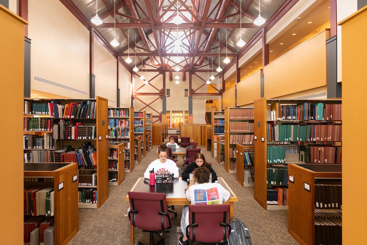 Tables on first floor of MSPAL with students surrounded by bookshelves.