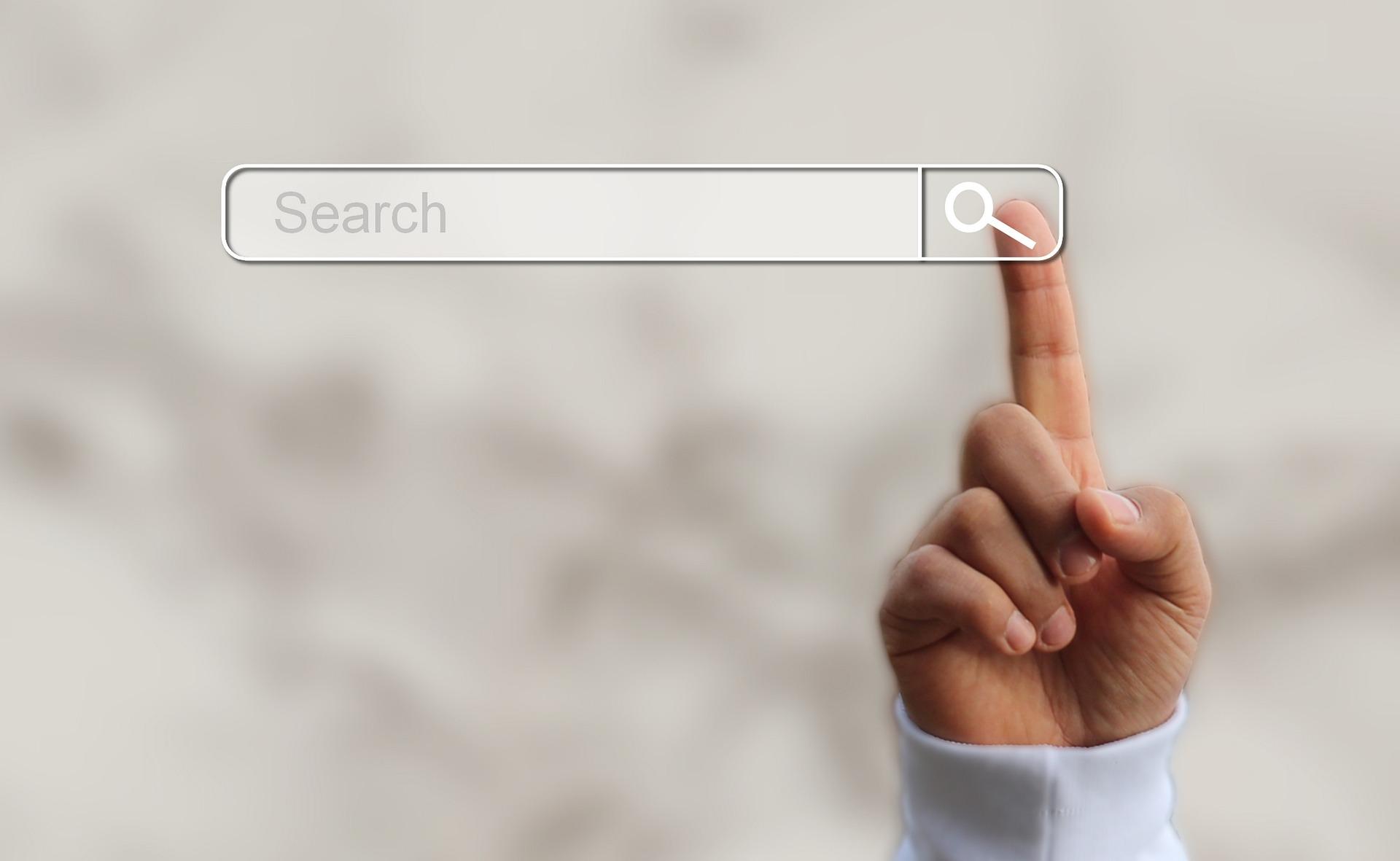 A pointer finger presses the magnifying glass icon on a search bar. 