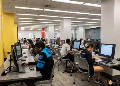 People seated in front of rows of computers.