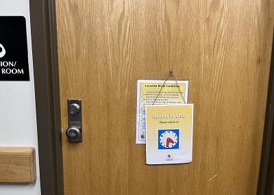 Exterior wooden door to the space, with sign showing that the room is currently in use