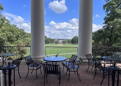 metal tables and chairs looking out onto a lawn and the sky