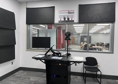 Podium with recording equipment, including video camera, monitor, and microphone