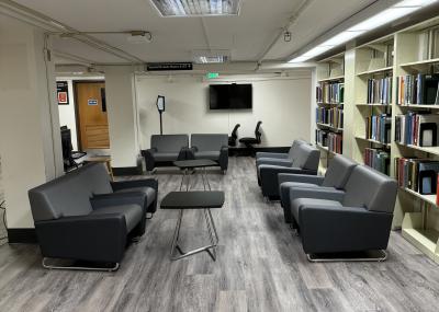 Lounge area with cushioned chairs and small tables. Not pictured: 2 computers at a small desk.